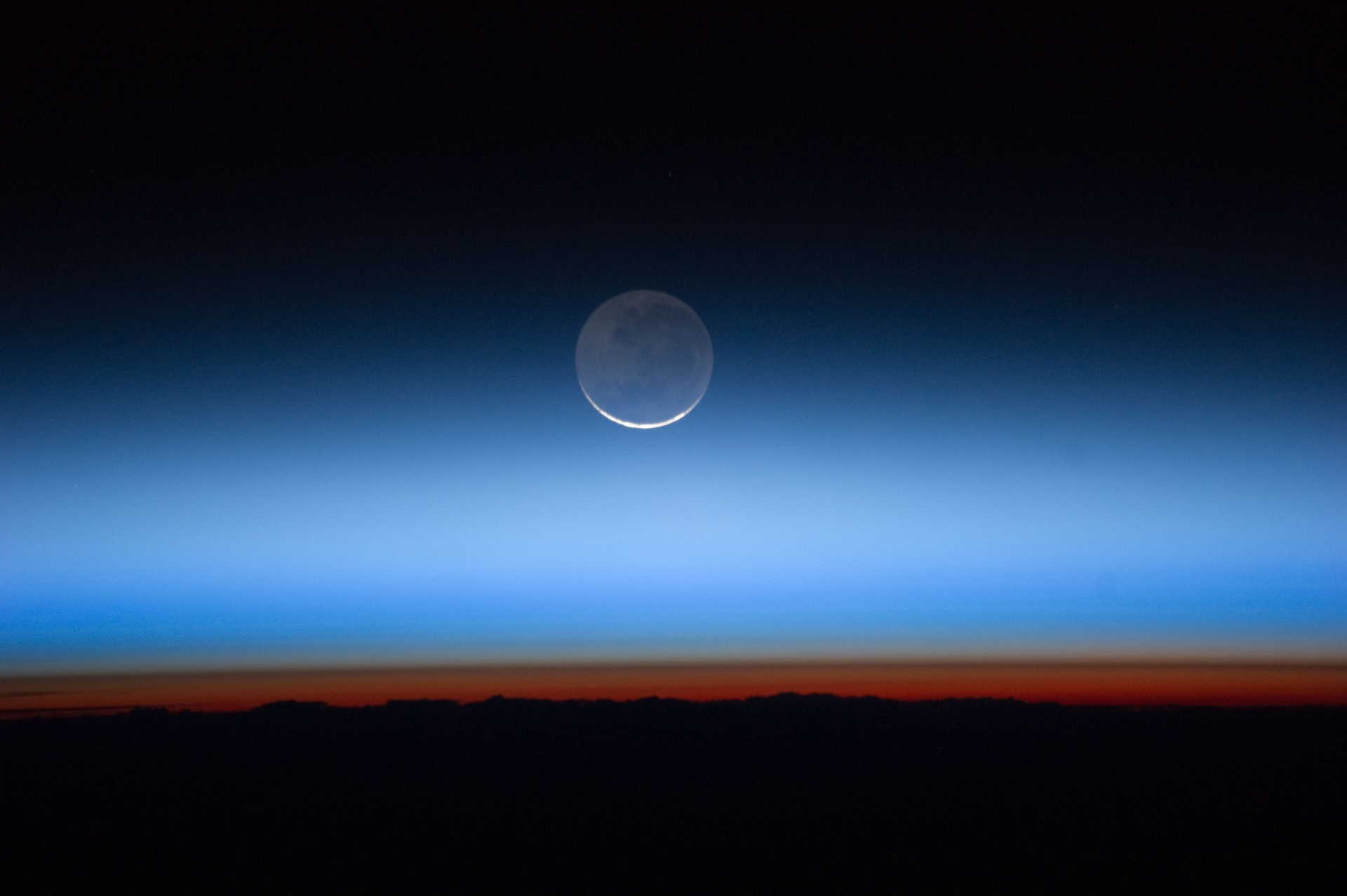 The Moon seen through Earth's thin blue atmosphere at twilight, from the International Space Station